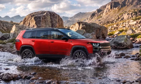 Kırmızı Jeep Cherokee Trailhawk, kayalık bir arazide sığ sudan geçerken