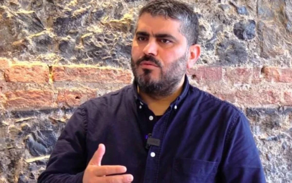 Ahmet Saymadi, taş duvar önünde otururken konuşuyor.
