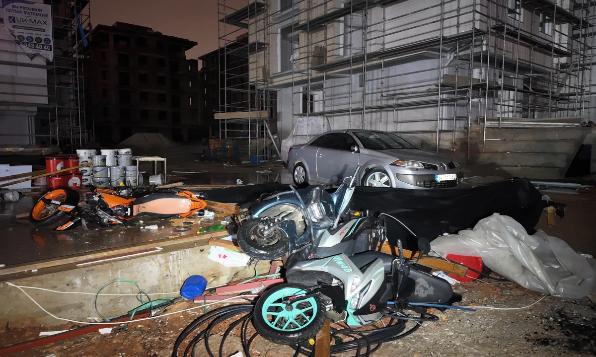 Şantiye alanında devrilmiş motosikletler, yerdeki eşyalar ve park halindeki otomobil