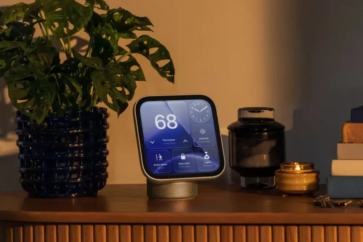 Ahşap bir konsol üzerinde duran, ekranda sıcaklık ve akıllı ev kontrolleri gösteren Apple HomeView ekranı