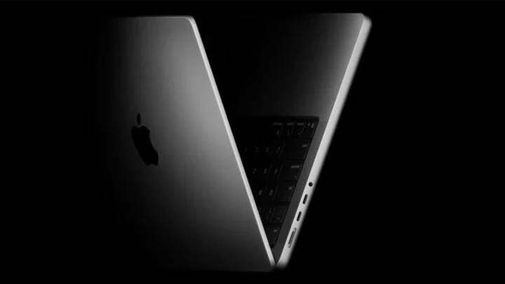 Koyu fonda açık konumda duran, Apple logosu görünen bir dizüstü bilgisayar