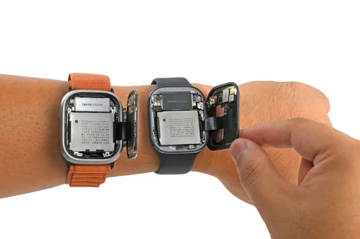 İki Apple Watch’un iç bileşenleri ve bataryaları görünür haldeyken bir saatten parça çıkarılıyor