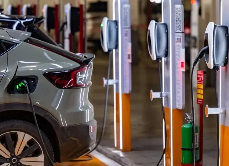Kapalı bir alanda şarj ünitelerinin yanında duran elektrikli otomobil
