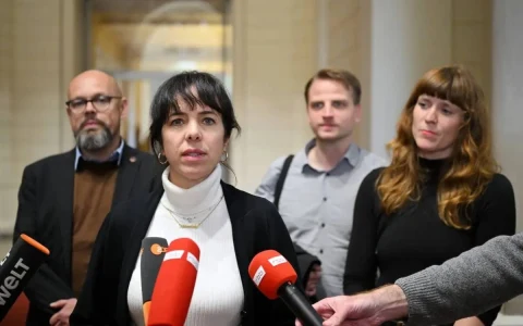 Mikrofonların önünde açıklama yapan kadın ve arkasında duran üç kişi