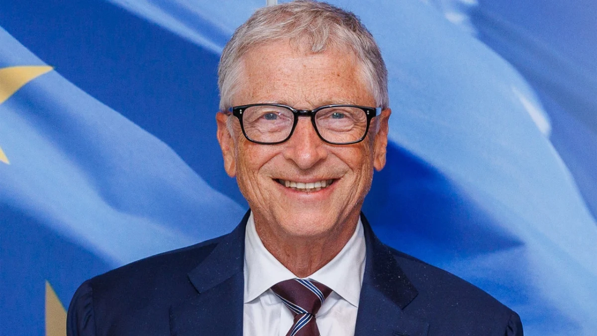 Bill Gates, mavi arka plan önünde takım elbiseyle gülümsüyor.