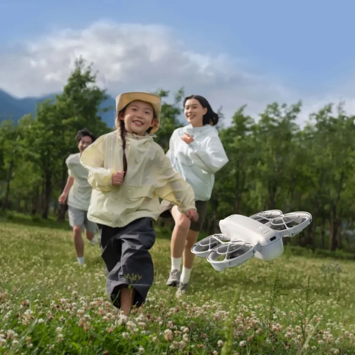 Çimenlik bir alanda uçan DJI Neo drone’un önünde koşan çocuklar