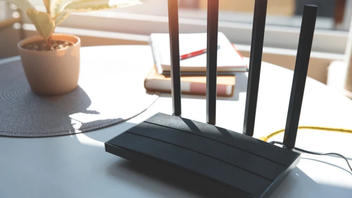 Masa üzerinde duran dört antenli siyah Wi-Fi yönlendirici