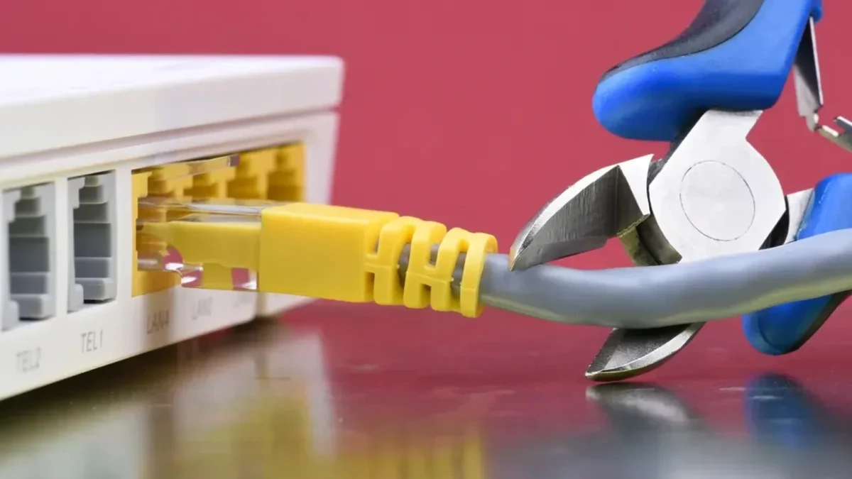 Mavi saplı kesici alet, sarı Ethernet kablosunu router bağlantısının yakınında kesiyor