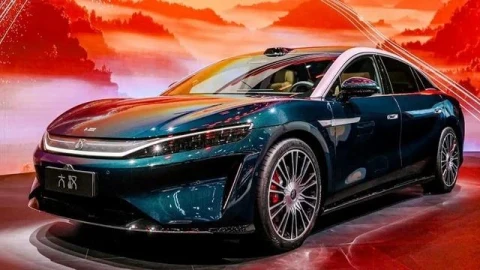 BYD Great Han koyu renkli gövdesiyle kırmızı tonlardaki bir fonda sergileniyor
