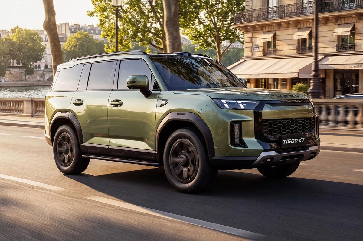 Yeşil Chery Tiggo X7 şehir caddesinde ilerliyor