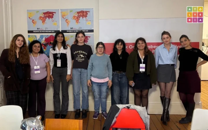 Atölye BİA ofisinde dokuz kişi, duvarda haritalar ve atölye afişi bulunan alanın önünde yan yana poz veriyor.