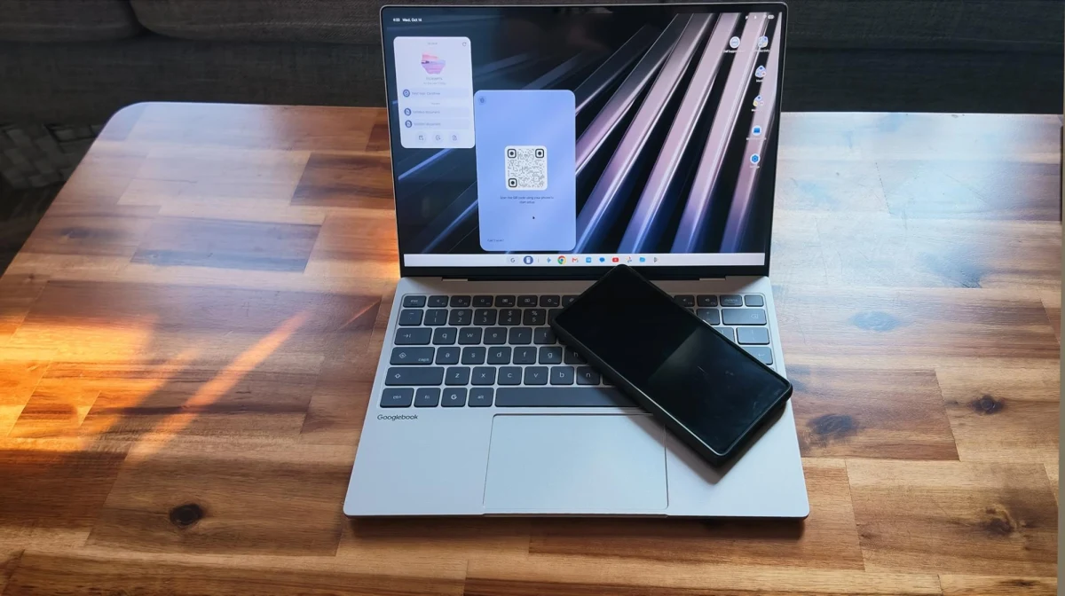 Ahşap masa üzerinde açık dizüstü bilgisayarın önünde duran akıllı telefon