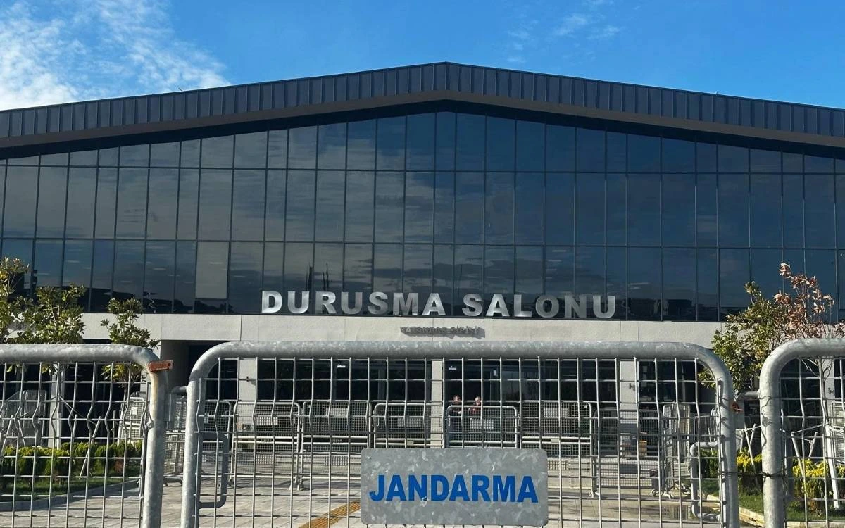 Jandarma bariyerlerinin arkasında, cephesinde “Duruşma Salonu” yazan bina