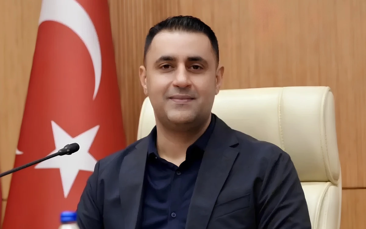 Çukurova Belediye Başkanı Emrah Kozay, makam odasında Türk bayrağının önünde oturuyor.