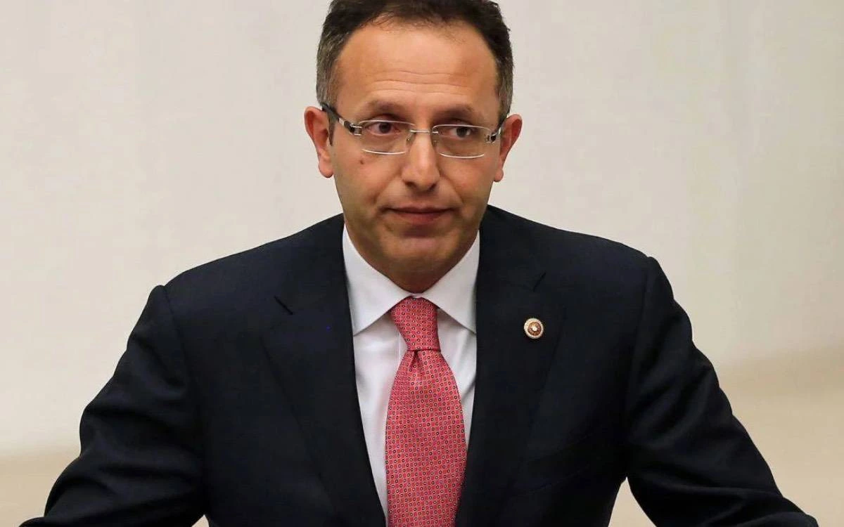 Ertan Aydın, koyu renk takım elbise ve kırmızı kravatla otururken
