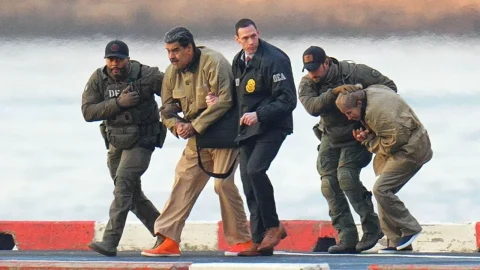 Silahlı görevliler, gözaltındaki Nicolás Maduro olduğu belirtilen kişiyi eşlik ederek götürüyor
