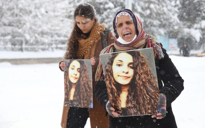 Kar yağışı altında Gülistan Doku’nun fotoğraflarını taşıyan iki kadın