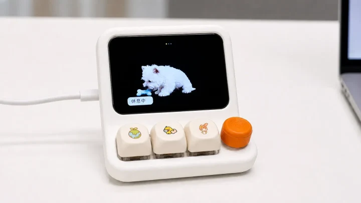 Küçük renkli ekranında beyaz bir karakter gösteren, fiziksel düğmeli HachimoDock masaüstü cihazı