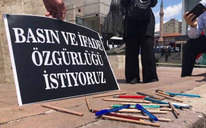 Yerde kalemlerin yanında “Basın ve ifade özgürlüğü istiyoruz” yazılı pankart
