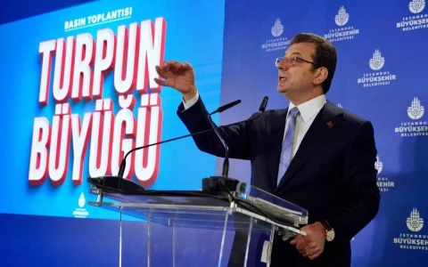 Ekrem İmamoğlu, İstanbul Büyükşehir Belediyesi logosunun bulunduğu fonda kürsüde konuşuyor.