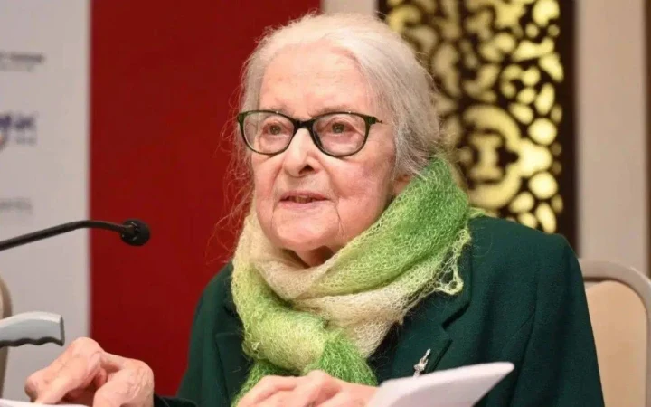 Prof. Dr. İoanna Kuçuradi, gözlük ve yeşil atkısıyla bir etkinlikte konuşurken