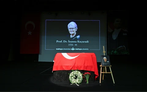 İoanna Kuçuradi’nin fotoğrafının yansıtıldığı sahnede Türk bayrağıyla örtülü bir platform, çiçekler ve portresi bulunuyor.