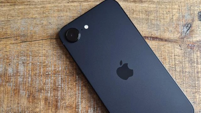 Ahşap yüzey üzerinde tek arka kamerası görünen koyu renkli Apple telefonu