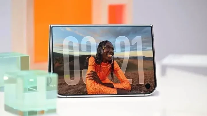 Yatay konumda duran bir akıllı telefonun ekranında 00:01 saati ve turuncu giysili bir kişi görünüyor