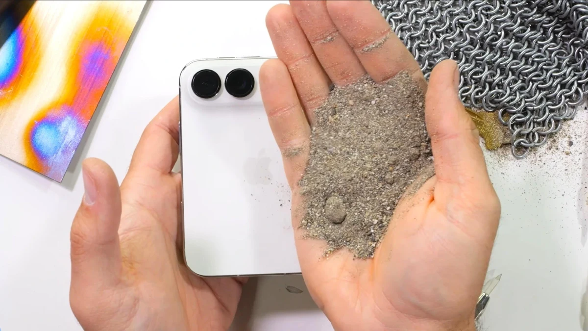 Bir elde kum, diğer elde beyaz katlanabilir telefon tutuluyor