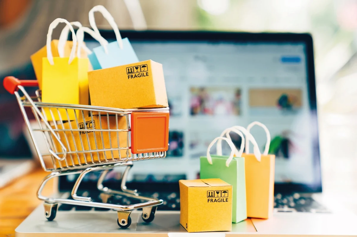 Bilgisayar ekranının önünde alışveriş sepeti ve paketler