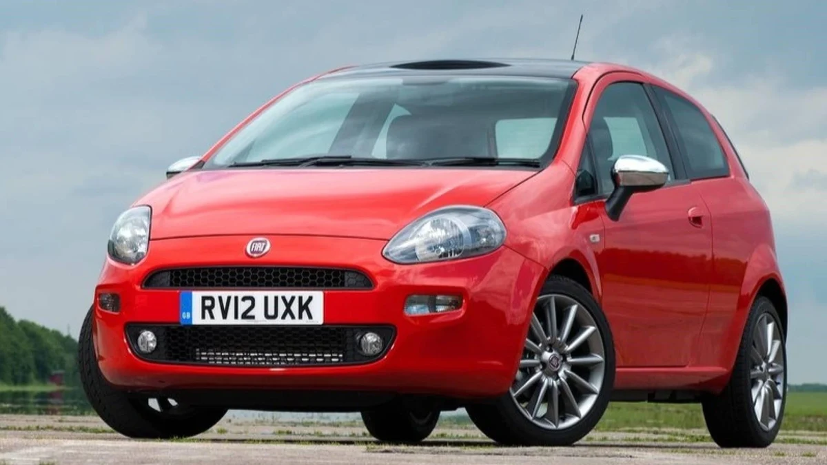 Kırmızı Fiat Punto, önden üç çeyrek açıyla dış mekânda görülüyor.