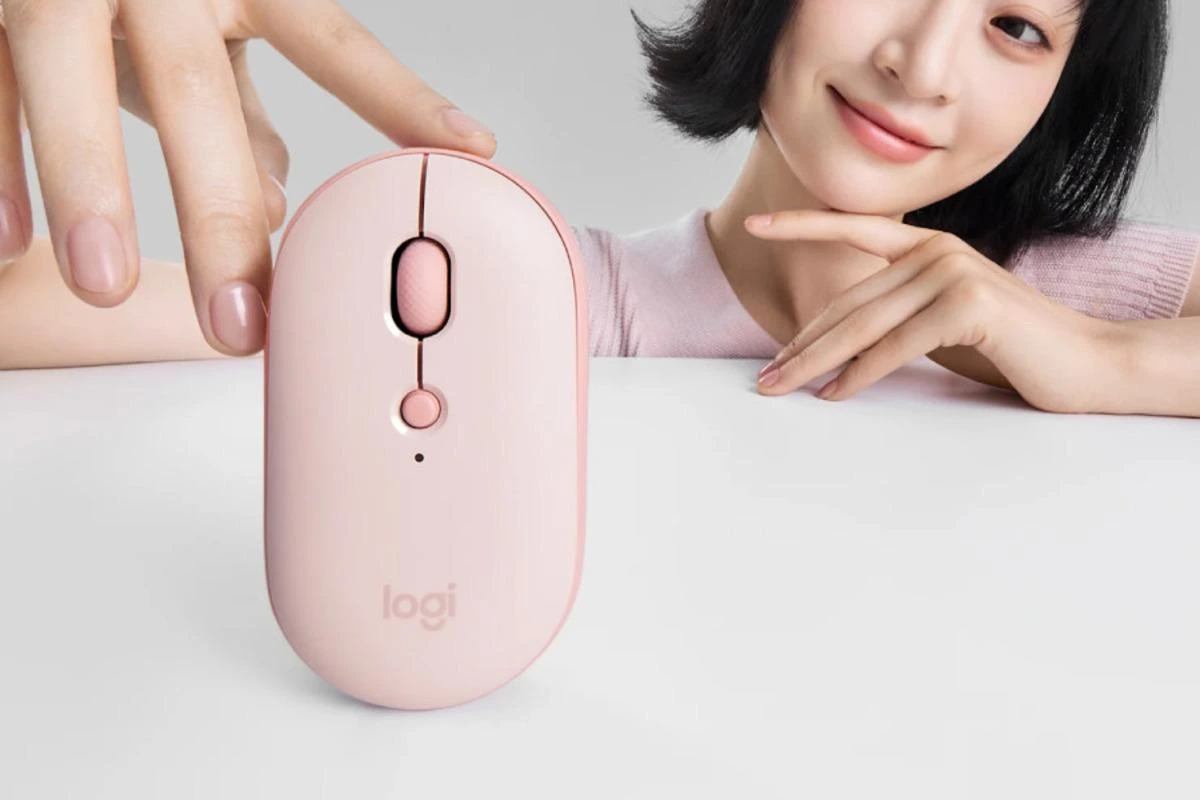 Pembe Logitech Pebble Up mouse’un üstten görünümü ve önünde duran bir kullanıcı