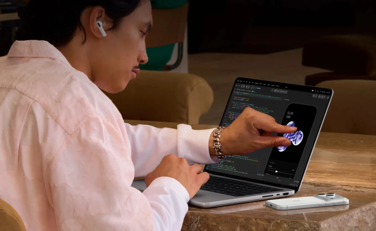 Bir kullanıcı MacBook ekranında parmağıyla uygulama arayüzünü kullanıyor