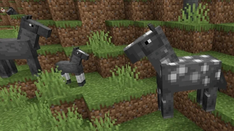 Minecraft’ta yetişkin atlar ve bir tay, çimenli arazide duruyor
