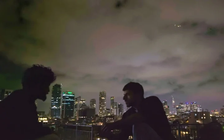 Gece Tel Aviv silüeti önünde oturan iki kişinin karanlık silüetleri