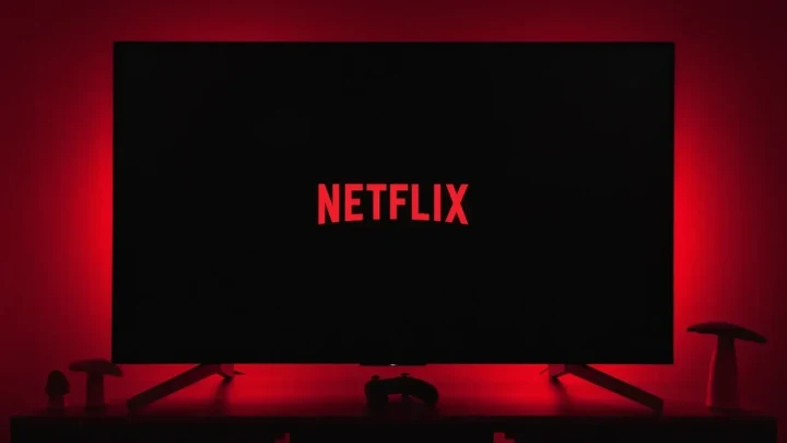 Kırmızı ışıkla aydınlatılmış bir odada Netflix logosu görünen televizyon