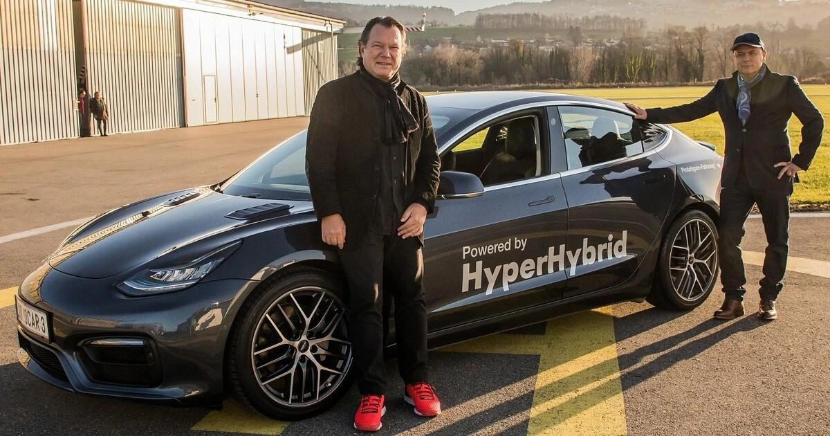 HyperHybrid yazılı Tesla Model 3’ün yanında duran iki kişi