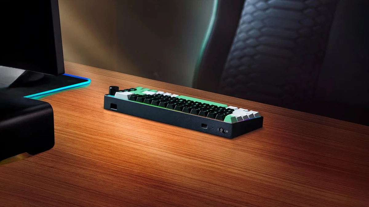 Razer Reclusa Mini 65% klavye ahşap masa üzerinde, bilgisayar ekranının yanında