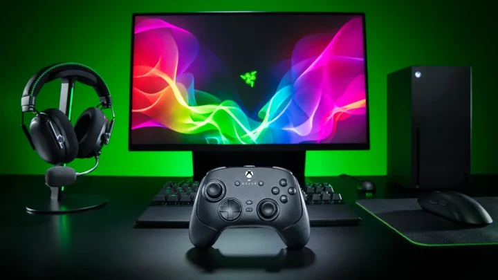 Razer oyun kumandası, monitör ve oyun ekipmanlarının bulunduğu yeşil ışıklı bir masa düzeni
