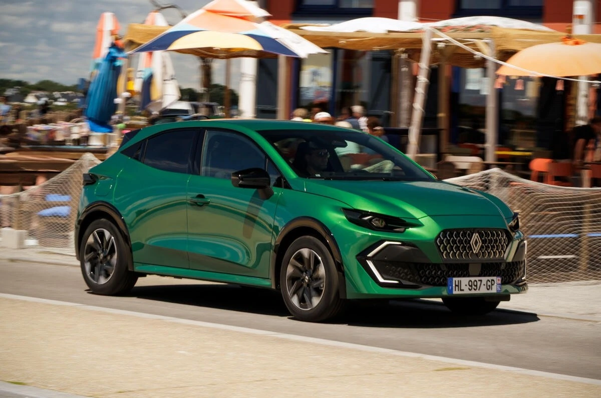 Yeşil Renault otomobili şehir içindeki bir caddede ilerliyor