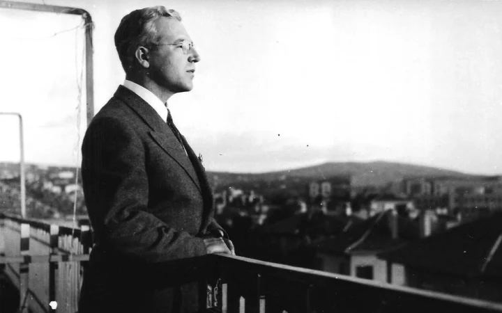 Sabahattin Ali, bir balkonda korkuluğa dayanmış halde dışarı bakıyor.