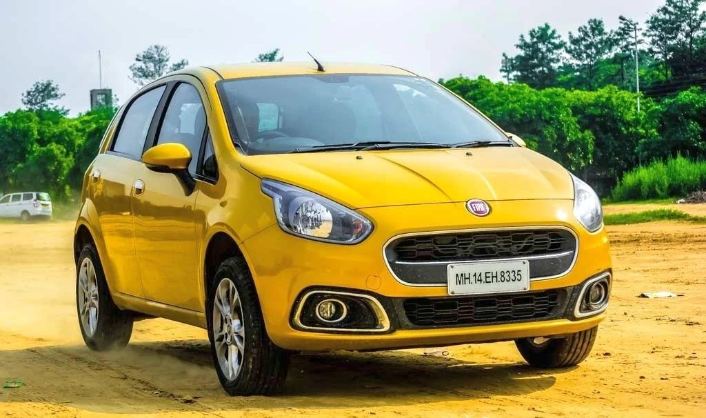 Sarı Fiat Punto, açık arazide önden üç çeyrek açıyla görüntüleniyor.