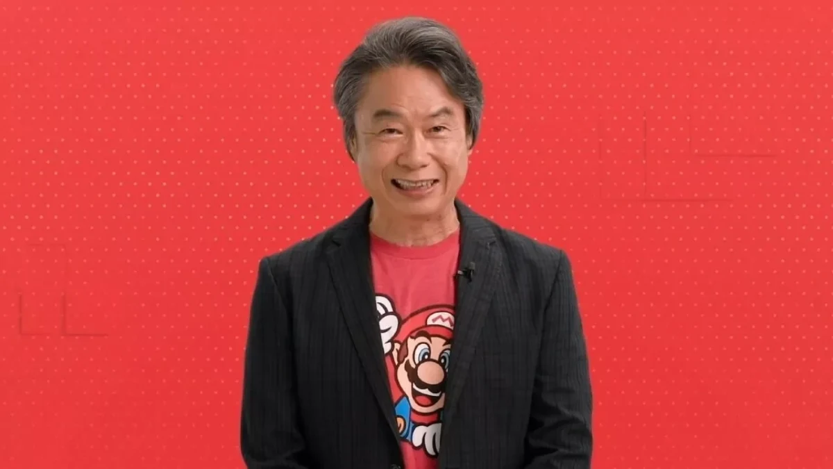 Shigeru Miyamoto, Mario baskılı tişörtü ve siyah ceketiyle poz veriyor