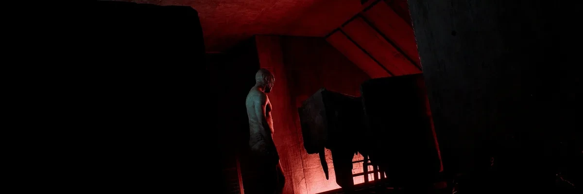 Silent Hill: Townfall’da kırmızı ışıkla aydınlanan karanlık bir iç mekân ve ayakta duran figür