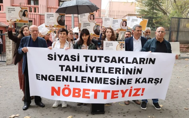 Siyasi tutsakların tahliyelerinin engellenmesine karşı nöbet tuttuklarını belirten pankartın arkasında duran bir grup kişi