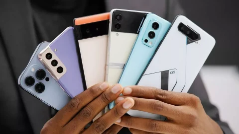 Bir kişinin ellerinde farklı renk ve tasarımlarda akıllı telefonlar