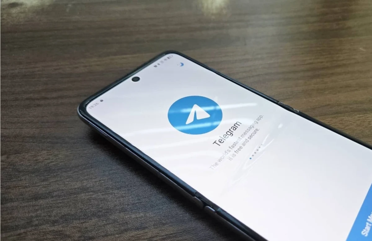 Ahşap yüzey üzerindeki akıllı telefonun ekranında Telegram uygulaması açık