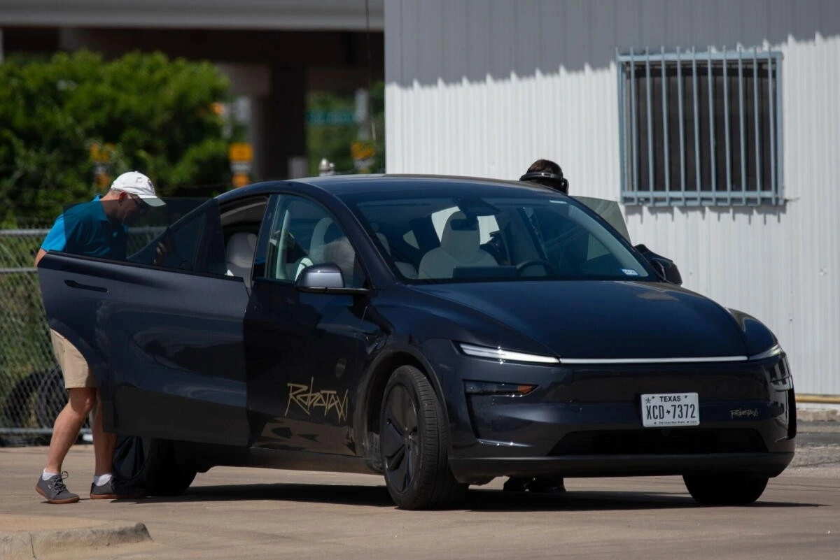 Bir kişi, park halindeki Tesla otomobilinin açık sürücü kapısının yanında duruyor