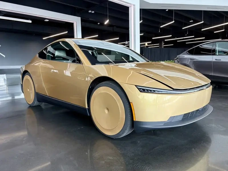 Bir iç mekânda sergilenen altın renkli Tesla Cybercab