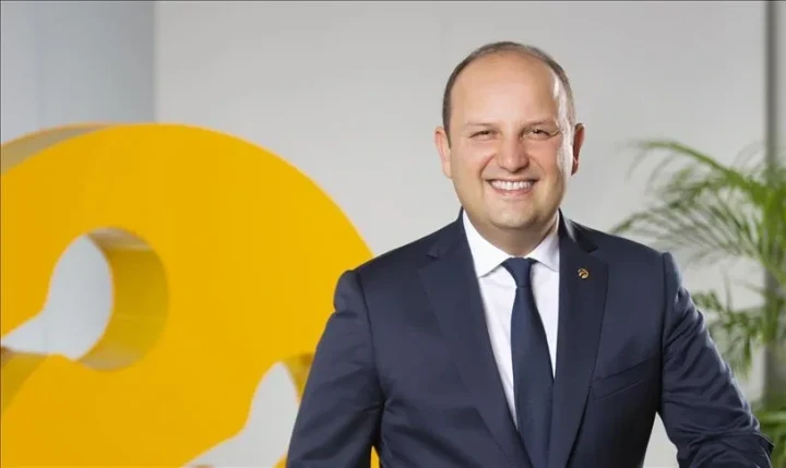 Turkcell yöneticisi, şirketin logosunun önünde poz veriyor